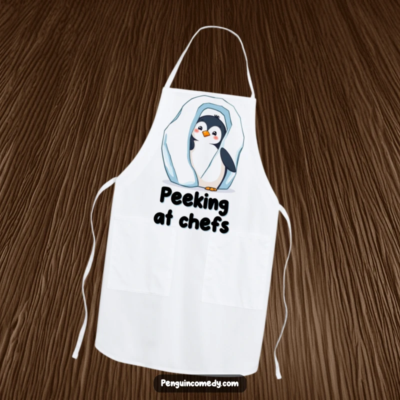 Funny apron with a curious penguin peeking from behind a large iceberg, observing the kitchen.