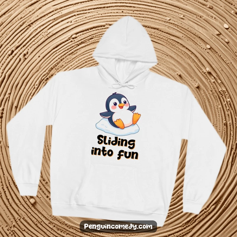 Funny happy penguin sliding down a small ice slope on its belly, featured on a cozy winter hoodie.