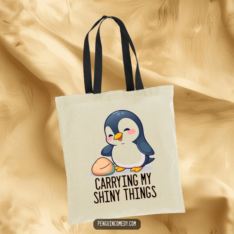 Funny penguin tote bag showing a playful penguin nudging a colorful pebble with its beak, ideal for carrying items with whimsical flair.